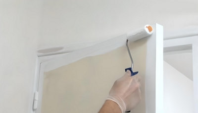 Personne qui peint la porte au rouleau