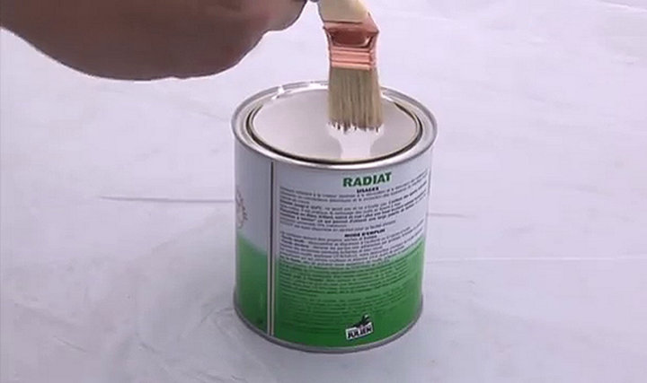 Personne raclant son pinceau sur le bord du pot