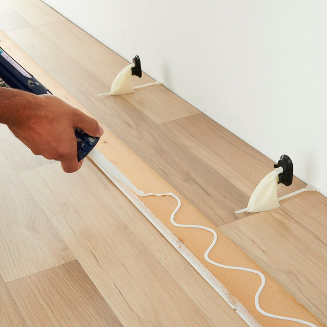 Personne appliquant cool sur l'arrière d'une plinthe en bois