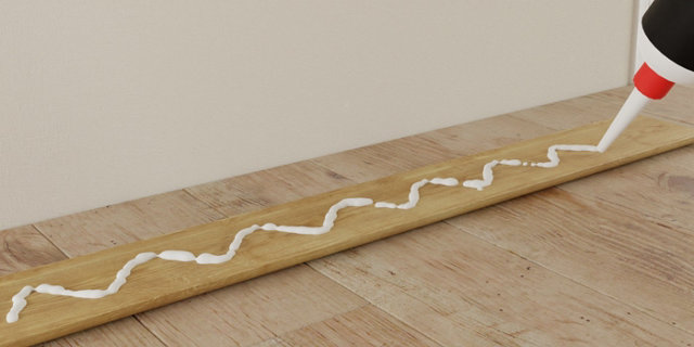 Application colle arrière de la plinthe en bois