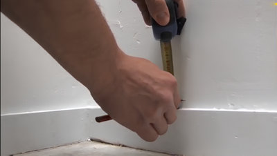 Mesure avec un mètre pour tracer repère au dessus de la plinthe