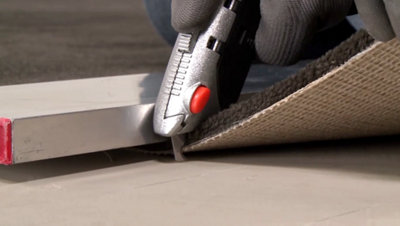 personne découpant moquette cutter