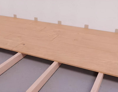 Placez des cales de bois le long du mur pour laisser un espace de dilatation de 5 mm. 