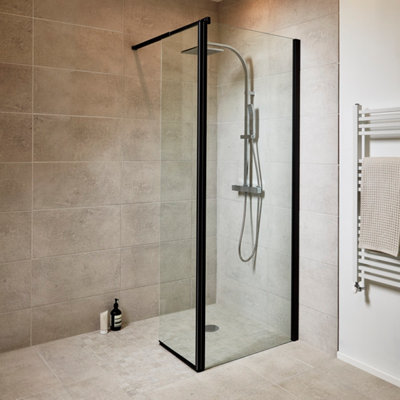 Douche à l'italienne avec paroi vitrée noire, carrelage beige et sèche-serviettes.