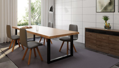Salle à manger table en bois et métal, chaises design, buffet en bois et mur carrelage blanc.