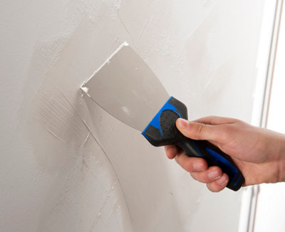 Rebouchage d'un mur à l'enduit avec un couteau à enduire