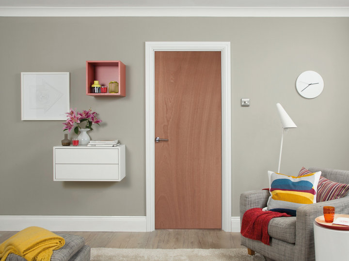 Porte en bois avec mu gris avec meubles au mur et fauteuil gris à droite