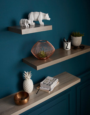 Tablette murale en bois sur un mur bleu foncé avec déco.
